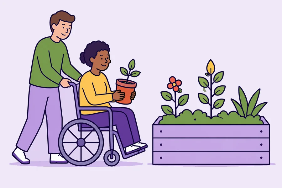 A worker and a person in a wheelchair together at a raised garden bed.